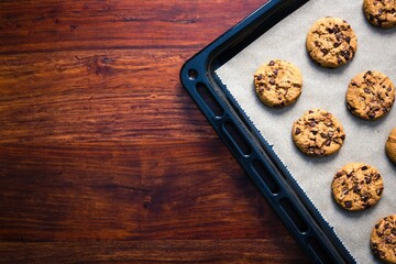 Tasty and freshly baked cookies on a baking tray on wooden background