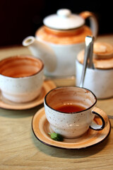 Beautiful tea utensils consisting of two cups and a teapot stand on a wooden table