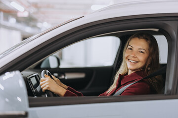 Portrait of a happy woman in her car, looking at camera.
