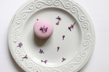 Obraz na płótnie Canvas cropped view of woman holding plate with pink delicious French macaroon or macaron with lilac flowers on white background