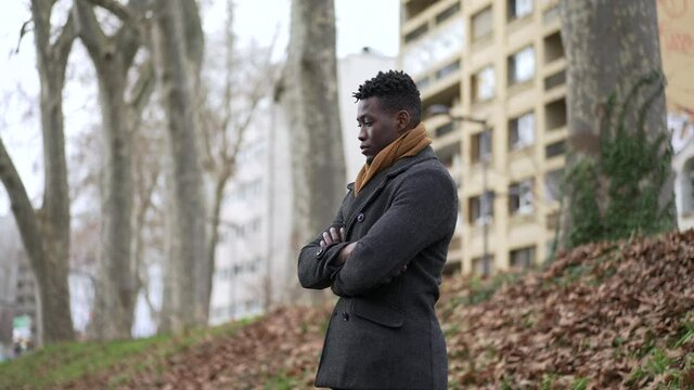 Pensive thoughtful African black man standing outside at park thinking about life