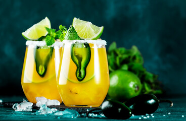 Margarita cocktail with tequila, mango juice, jalapeno pepper, lime and salt, blue background