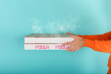 Deliveryman holds bizza boxes ready to be delivered . cyan background