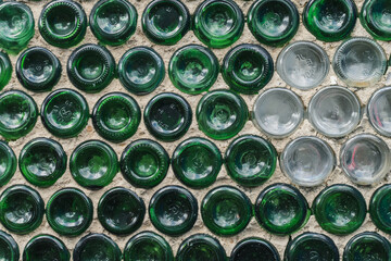 Wall of the house is made  of used green and white glass bottles. Creative background.