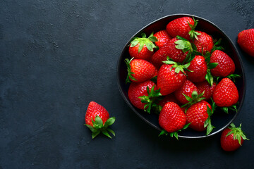 Fresh ripe organic strawberry in a black bowl .