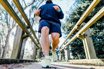 Young adult man pr sport professional running through a park in spring or summer training at sunset...