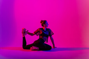 Beautiful female dancer wearing black and high heels while performing pole dance tricks