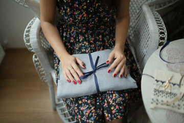 Woman Holding Softly Wrapped Gift with Navy Ribbon on Her Lap