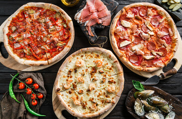 Variety of meat pizzas with sausage, ham, prosciutto, salami, chicken fillet, pepperoni, shrimps,...