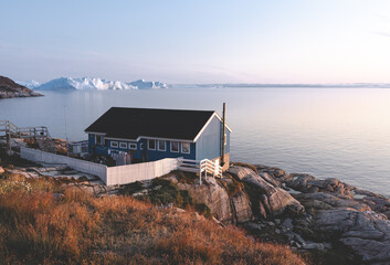 The colorful house of Ilulissat, Greenland. Kangia icefjord covered in fog in background with...