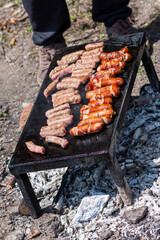 Grilling meat on bbq stone grill in nature. Preparing cevapi and kobasice or kebab and sausages for family and friends. Famous traditional Bosnian food