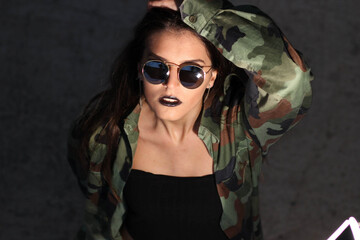 Cool young caucasian female in a camo jacket posing outdoors