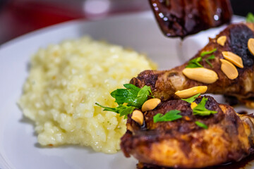 Thai chicken decorated with fresh parsley and peanuts on plate with blured rice. Female chef decorating plate with food