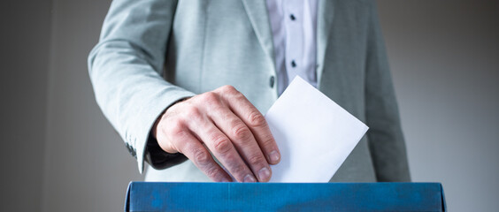 male hand putting vote in ballot