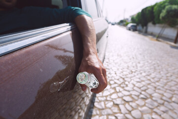 Drunk driver hand with a bottle of vodka. Driving under alcohol influence. Dangerous driving concept