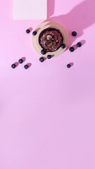 Vertical banner with gluten free cake with blueberry and carob. Homemade chocolate cake with raw berries on modern circle and square podiums on pink background. Creative food. Top view, copy space