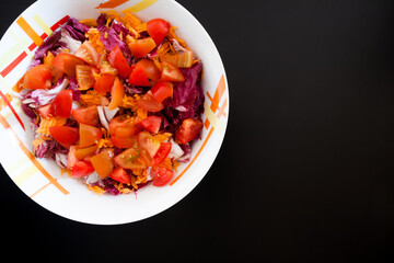Salad with carrots and tomatoes on black table, top view