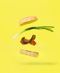 Floating burger with meat and green onion isolated on yellow background. Creative food concept.