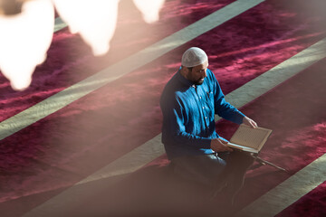 muslim man praying Allah alone inside the mosque and reading islamic holly book