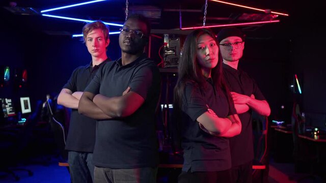 The cyber team, consisting of three guys and a girl, confidently looks at the camera and folds a arms over a chest