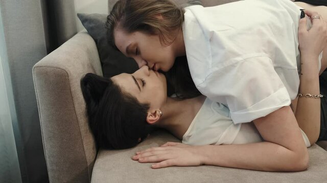 Two young stylish cool women, affectionate lesbian lgbtq couple dating in love relaxing at home