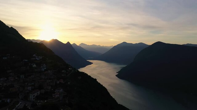 Dramatic aerial footage of the sunset over lake Lugano and the Monte bre village in canton Ticino, Switzerland with the italian alps in the background