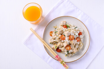 Fried rice with tofu, mung bean sprouts and tomato on dish eating with orange juice on white background, Asian healthy vegan food