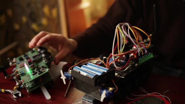 DIY, the machine on electronic control. Home experiments, robotics, smart engineer. Toy for the child. A man collects repairs to an electronic device. Wires, motherboard, batteries closeup sunlight