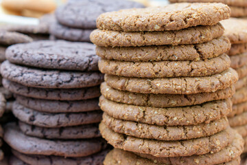 Light and dark flat biscuits with additives. Round biscuits are stacked in piles. 