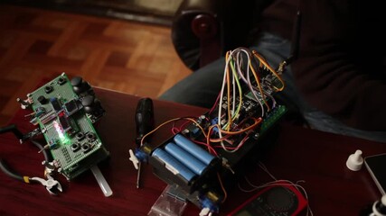 DIY, the machine on electronic control. Home experiments, robotics, smart engineer. Toy for the child. A man collects repairs to an electronic device. Wires, motherboard, batteries closeup