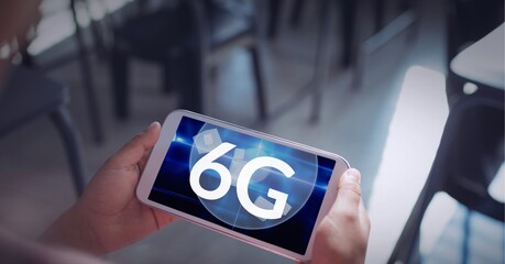 Composition of the word 6g over a person holding a smartphone in background