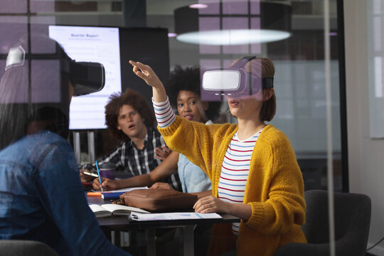 Diverse group of creative colleagues using vr headset in meeting room