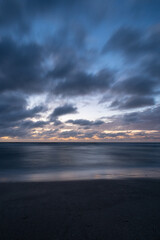 Fototapeta premium Dramatic long exposure of some clouds over the sea at the blue hour