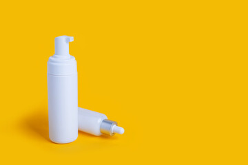 cosmetic bottles on yellow background with copy space