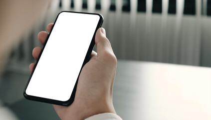 Mockup image of hand holding mobile phone with blank white screen in home