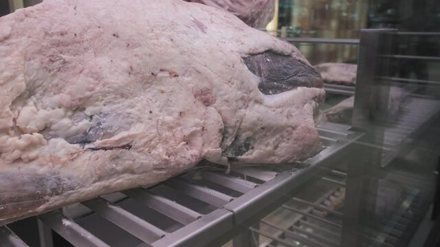 Large portions of raw, butchered beef carcass. Red meat is in a big transparent refrigerator in the supermarket. The concept of meat eating, consumption of animal protein and essential amino acids