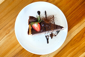 Homemade sweet sliced chocolate crepes cake with Strawberry and Cookies close-up on a plate. selective focus
