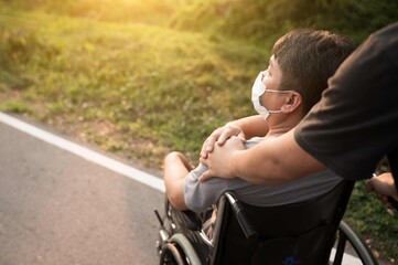 Paralyzed,disabled or handicapped man sitting relax on a wheelchair in nature park.Disabled handicapped man has a hope with his family