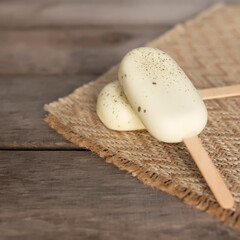 White shiny cookie ice creams on a stick on wooden background
