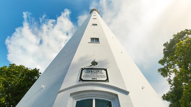 Anyer, Indonesia-March 31, 2021: a historic lighthouse building that has a white color with several windows. The sky background is blue and there are colored clouds called the Mercusuar Cikoneng