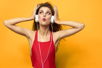 Emotional woman in white headphones listens to music fun lifestyle yellow background