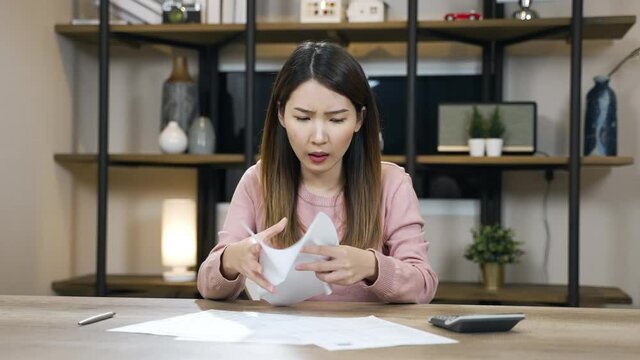 Slow motion frustrated Asian woman looking at the paper bills upset throwing crumpled paper away.  mental problems, failure reaction