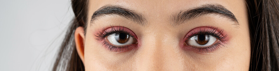 Macro shot of woman eye makeup with red eyeshadow. Close-up of woman eyelashes. Panoramic shot.