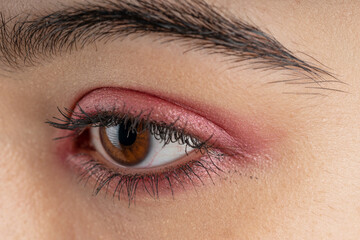 Macro shot of woman eye makeup with red eyeshadow. Close-up of woman eyelashes. Horizontal shot.