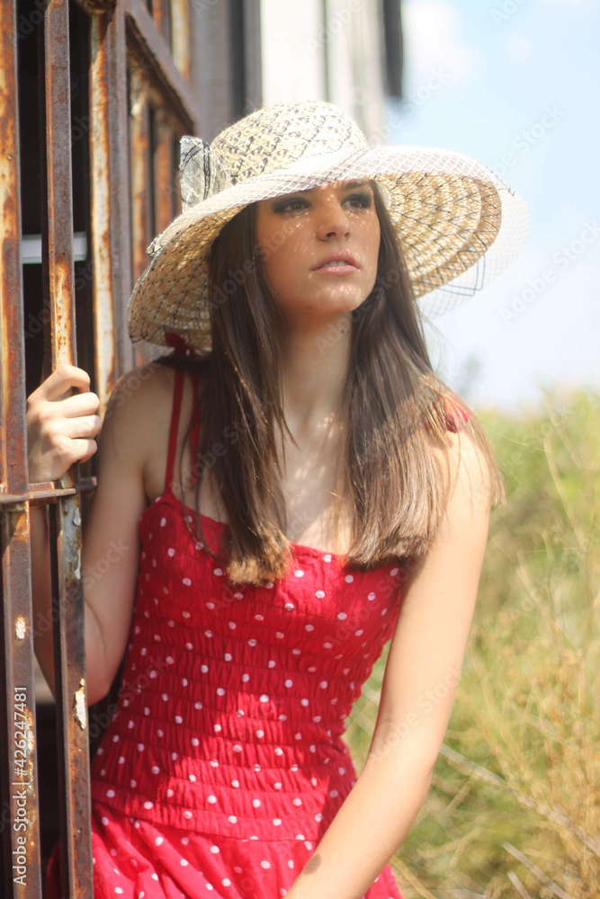 Canvas Prints Vertical shot of a beautiful young Caucasian lady wearing a red polka-dot dress with a summer hat