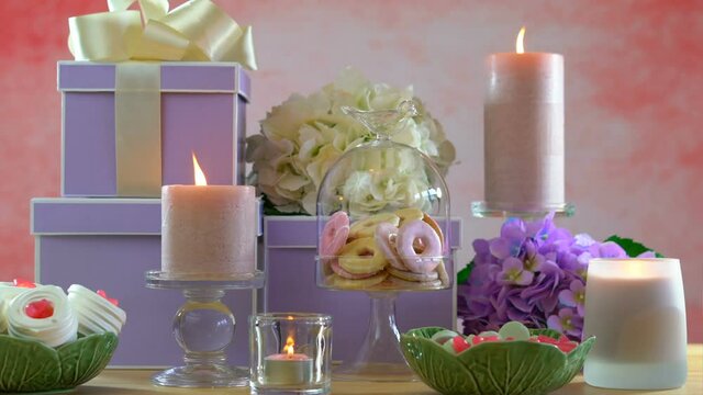 4k Mother's Day or Birthday party table with stack of gifts, cookies, flowers, and candles. Dolly reveal to static shot.