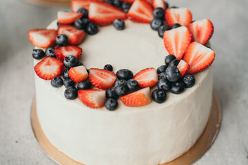 Fresh homemade cake with cheese cream and wild berries. Strawberry and blueberry cake. Beautiful cake on a tray
