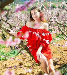 Portrait of happy girl in red dress in a blooming spring garden
