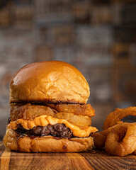 Hambúrguer de carne com creme de queijo tipo cheddar e anéis de cebola