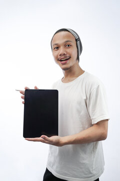 Image of cheerful young designer with skullcaps holding and using a tablet isolated on white background